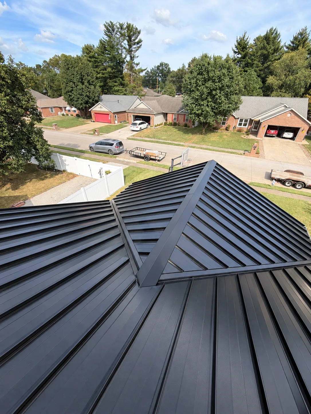 Close roof-level view of dark standing seam metal panels and a hip ridge detail
