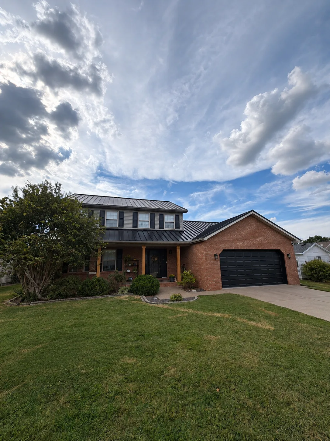 Black standing seam metal roof on a two-story brick home in Evansville, Indiana