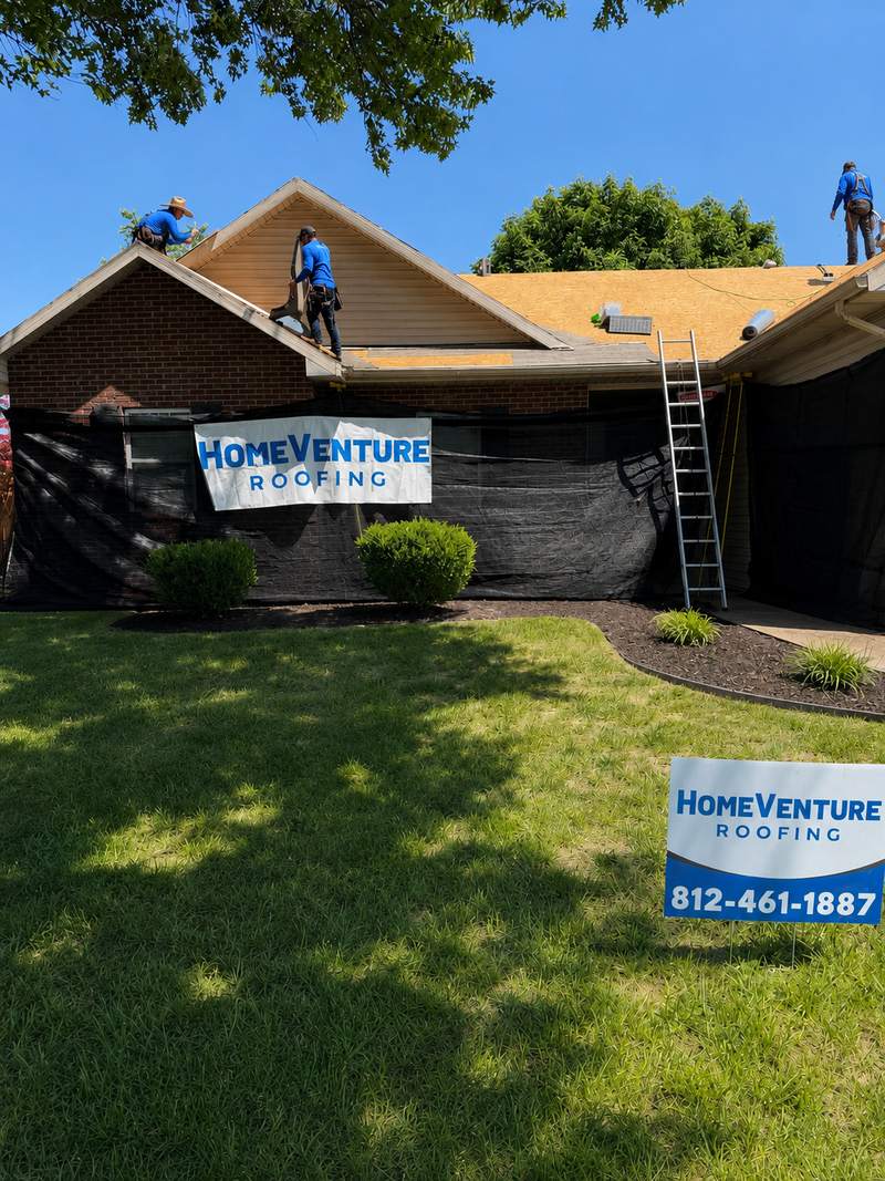 Branded HomeVenture crew working on a roof with yard sign visible in Evansville.